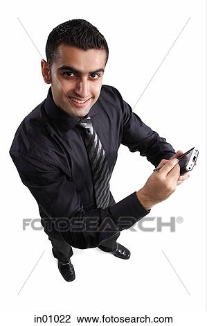 Stock Image - Executive using PDA, looking up at camera. Fotosearch