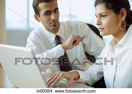 Executives working together, woman using laptop, man next to her View Large Photo Image Picture - Executives working together, woman using laptop, man next to her. Fotosearch