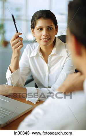 Stock Image - Female executive talking with man in front of her. Fotosearch