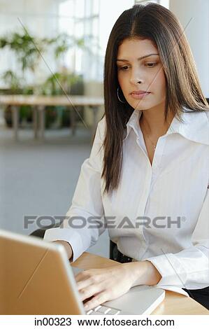 Stock Image - Female executive using laptop, portrait. Fotosearch