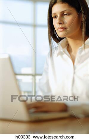 Stock Image - Female executive working on laptop. Fotosearch