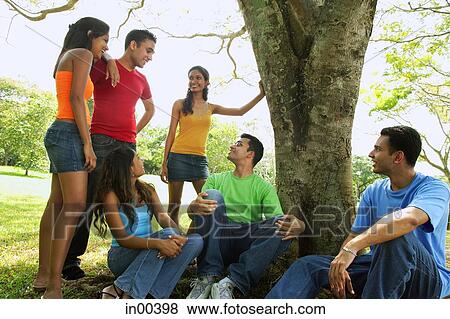 Group of young adults sitting in park View Large Photo Image Stock Photo - Group of young adults sitting in park. Fotosearch