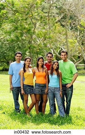 Group of young adults standing in park, looking at camera View Large Photo Image Stock Image - Group of young adults standing in park, looking at camera. Fotosearch