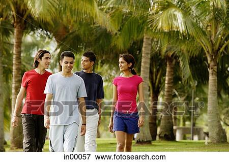 Group of young adults walking in park View Large Photo Image Stock Photo - Group of young adults walking in park. Fotosearch