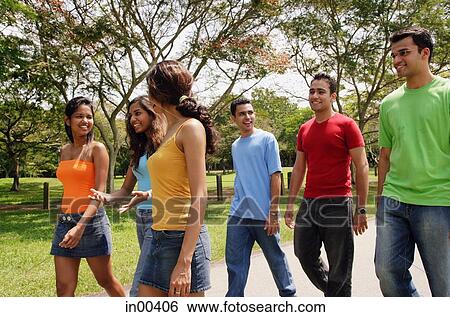 Group of young adults walking in park View Large Photo Image Stock Photograph - Group of young adults walking in park. Fotosearch