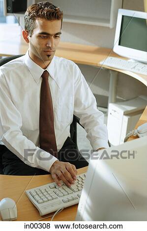 Male executive at desk, facing computer View Large Photo Image Stock Photo - Male executive at desk, facing computer. Fotosearch
