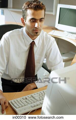 Male executive at desk, using computer View Large Photo Image Stock Image - Male executive at desk, using computer. Fotosearch