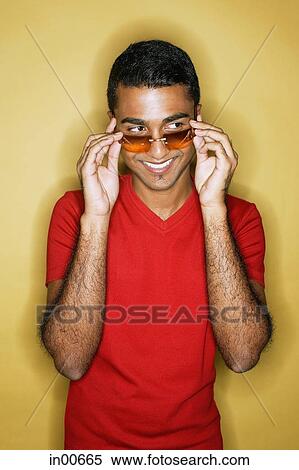 Stock Photography - Man adjusting sunglasses, smiling. Fotosearch