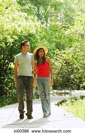 Man and woman walking side by side in park View Large Photo Image Stock Photograph - Man and woman walking side by side in park. Fotosearch