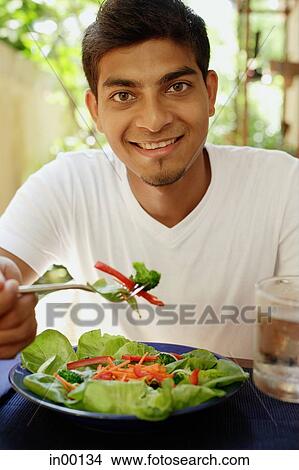 Man eating salad, looking at camera View Large Photo Image Picture - Man eating salad, looking at camera. Fotosearch