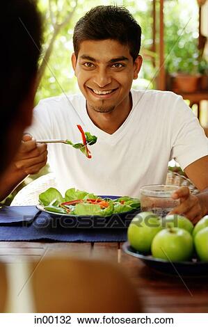 Man eating salad, looking at person opposite him View Large Photo Image Stock Image - Man eating salad, looking at person opposite him. Fotosearch