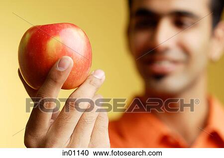 Stock Image - Man holding apple in hand, selective focus. Fotosearch