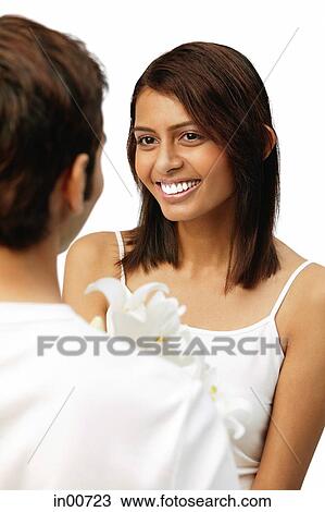 Stock Image - Man holding flowers, facing woman. Fotosearch