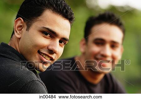 Man looking over shoulder at camera, another person in the background View Large Photo Image Picture - Man looking over shoulder at camera, another person in the background. Fotosearch