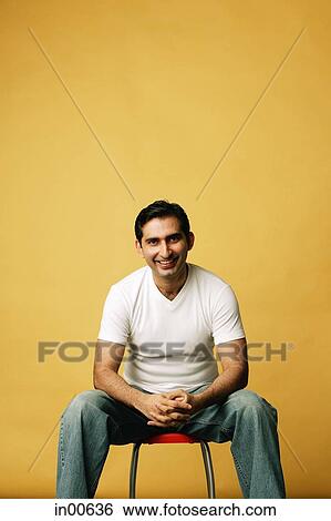 Man sitting on stool, looking at camera View Large Photo Image Stock Photograph - Man sitting on stool, looking at camera. Fotosearch