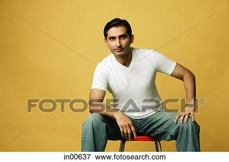 Man sitting on stool, looking at camera, hand on knee View Large Photo Image Stock Photo - Man sitting on stool, looking at camera, hand on knee. Fotosearch