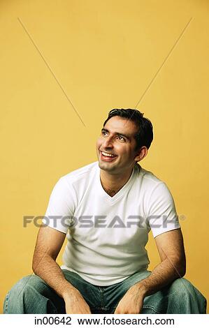 Man sitting, smiling, looking away View Large Photo Image Stock Image - Man sitting, smiling, looking away. Fotosearch