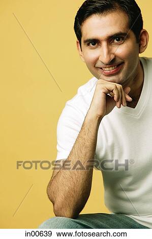 Stock Photo - Man smiling at camera, hand on chin. Fotosearch