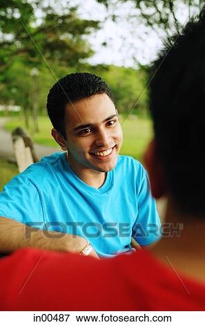 Stock Photo - Man smiling, facing another person. Fotosearch