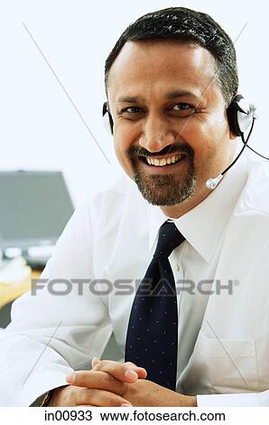 Stock Image - Man using headset, smiling at camera. Fotosearch