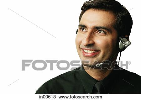 Stock Photo - Man using headset, smiling, looking away. Fotosearch