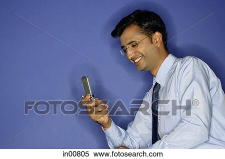 Stock Photography - Man using mobile phone, smiling. Fotosearch