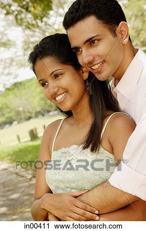 Stock Image - Portrait of a couple, man embracing woman from behind. Fotosearch
