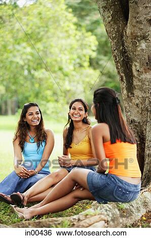 Three young women, sitting at base of tree in park, smiling View Large Photo Image Stock Photograph - Three young women, sitting at base of tree in park, smiling. Fotosearch
