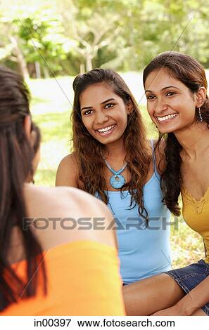 Three young women, sitting, over the shoulder view View Large Photo Image Stock Photo - Three young women, sitting, over the shoulder view. Fotosearch