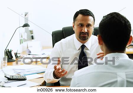 Stock Photograph - Two businessmen in office having a discussion. Fotosearch