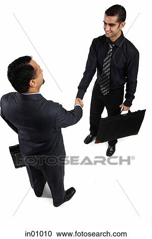 Stock Image - Two businessmen shaking hands, high angel view. Fotosearch