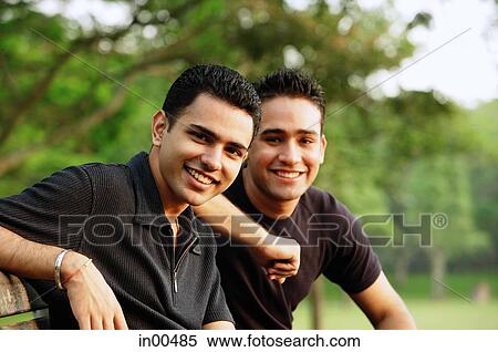 Stock Photography - Two men sitting side by side, looking at camera. Fotosearch