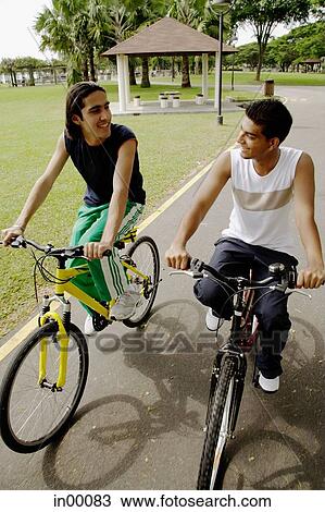Two young men cycling side by side View Large Photo Image Stock Image - Two young men cycling side by side. Fotosearch