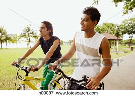 Two young men on bicycles, looking away View Large Photo Image Stock Photo - Two young men on bicycles, looking away. Fotosearch
