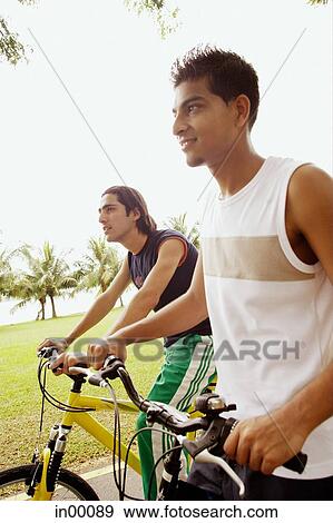 Two young men on bicycles, side by side, looking away View Large Photo Image Stock Photo - Two young men on bicycles, side by side, looking away. Fotosearch