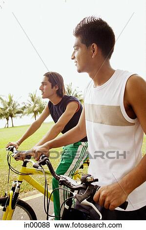 Stock Photo - Two young men on bicycles, sideview. Fotosearch