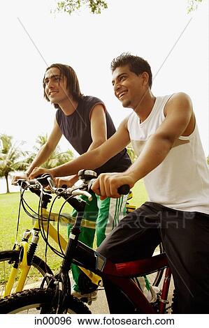 Two young men on bicycles View Large Photo Image Stock Photograph - Two young men on bicycles. Fotosearch