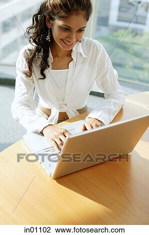 Woman at desk, using laptop View Large Photo Image Stock Image - Woman at desk, using laptop. Fotosearch