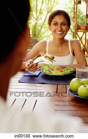 Woman at table with plate of salad, looking at man across from her View Large Photo Image Stock Image - Woman at table with plate of salad, looking at man across from her. Fotosearch
