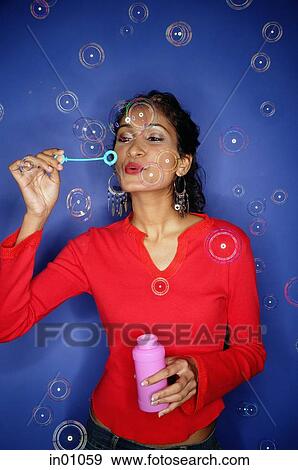 Woman blowing bubbles from bubble wand View Large Photo Image Stock Photo - Woman blowing bubbles from bubble wand. Fotosearch
