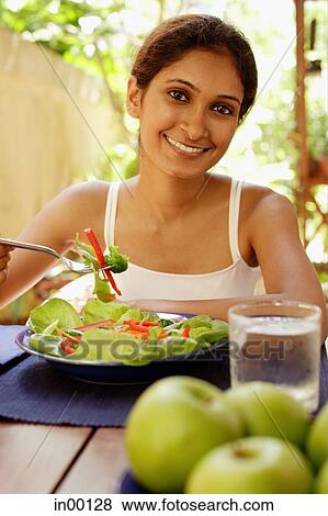 Stock Photo - Woman eating salad, looking at camera. Fotosearch