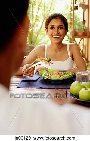 Woman eating salad, looking at man across from her View Large Photo Image Stock Photo - Woman eating salad, looking at man across from her. Fotosearch