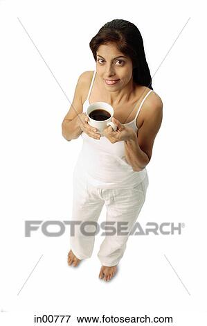 Stock Photo - Woman holding cup of coffee, looking up at camera. Fotosearch