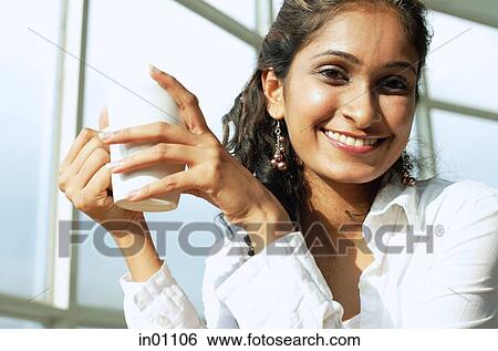 Woman holding mug, smiling at camera View Large Photo Image Stock Photograph - Woman holding mug, smiling at camera. Fotosearch