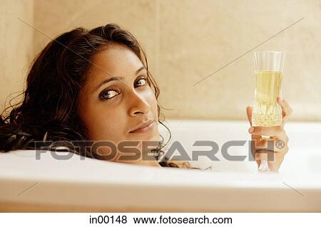 Stock Photo - Woman in bathtub, holding champagne glass. Fotosearch