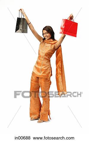 Stock Photo - Woman in Indian clothing, arms outstretched, carrying shopping bags. Fotosearch