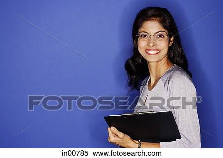 Stock Photography - Woman looking at camera, carrying clipboard. Fotosearch