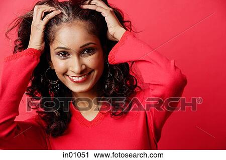Stock Image - Woman looking at camera, pulling hair back from face. Fotosearch