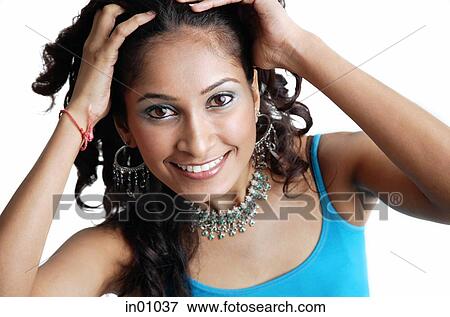 Stock Photo - Woman looking at camera, pulling hair back with her hands. Fotosearch