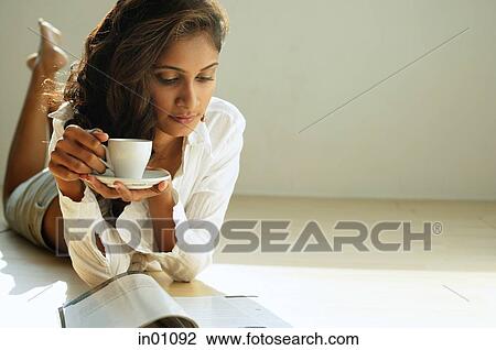 Woman looking at magazine, holding cup and saucer View Large Photo Image Stock Image - Woman looking at magazine, holding cup and saucer. Fotosearch